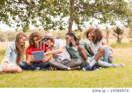 Happy friends in the park looking at tablet Happy friends in the park looking at tablet 14086929