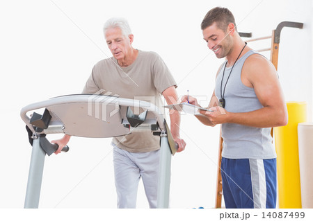 Senior man on treadmill with trainer 14087499