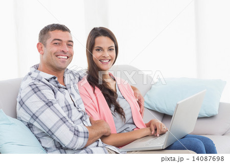 Happy couple with laptop sitting on sofa Happy couple with laptop sitting on sofa 14087698