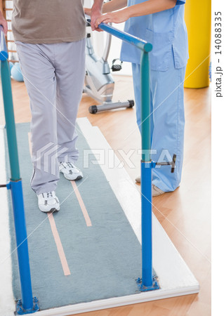 Senior man walking with therapist help Senior man walking with therapist help 14088335