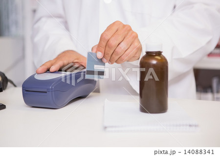 Pharmacist using keypad with credit card 14088341