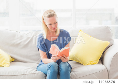 Woman reading book on sofa Woman reading book on sofa 14088376