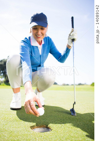 Smiling lady golfer kneeling on the putting green Smiling lady golfer kneeling on the putting green 14089142