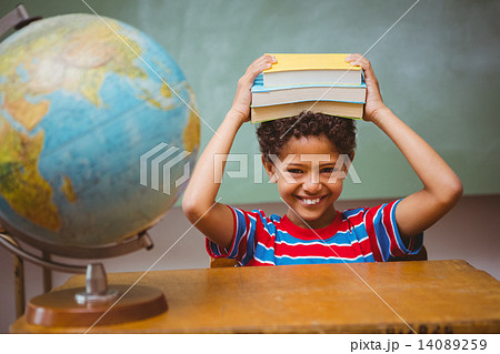 Little boy holding books over head in classroom Little boy holding books over head in classroom 14089259