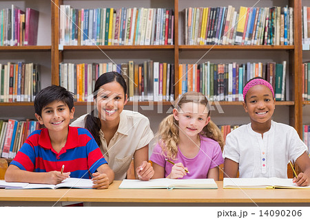Pretty teacher helping pupils in library 14090206