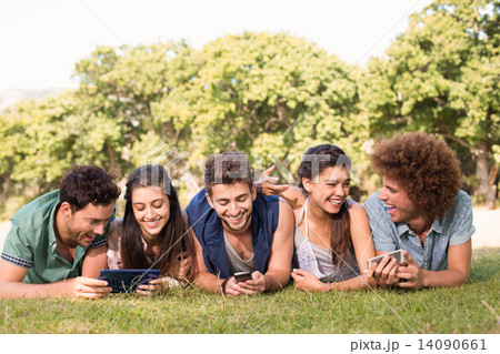 Happy friends in the park using their phones 14090661