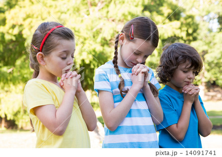 Children saying their prayers in park Children saying their prayers in park 14091741