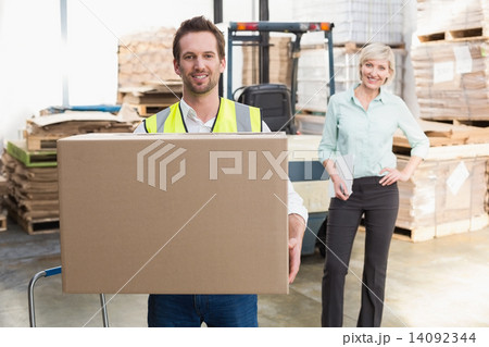 Smiling warehouse worker carrying box Smiling warehouse worker carrying box 14092344