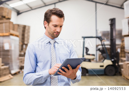 Manager using digital tablet in warehouse 14092553