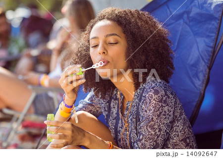 Carefree hipster blowing bubbles in tent 14092647