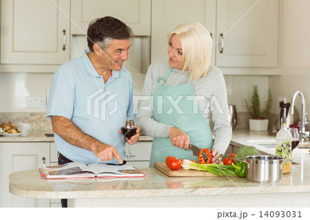 Happy mature couple having red wine while making dinner Happy mature couple having red wine while making dinner 14093031