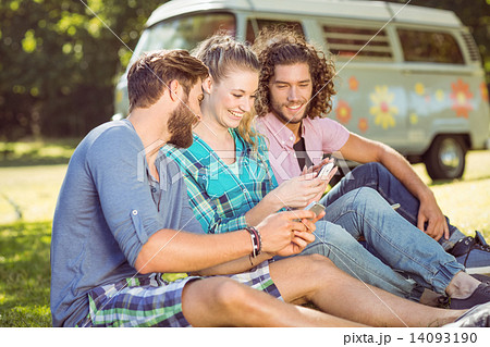 Hipsters sitting on the grass texting Hipsters sitting on the grass texting 14093190