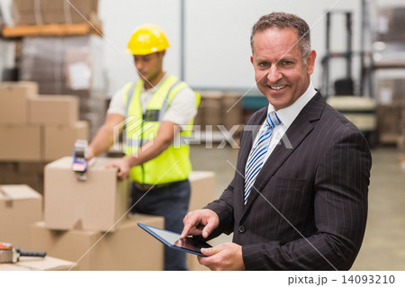 Boss using digital tablet in warehouse 14093210