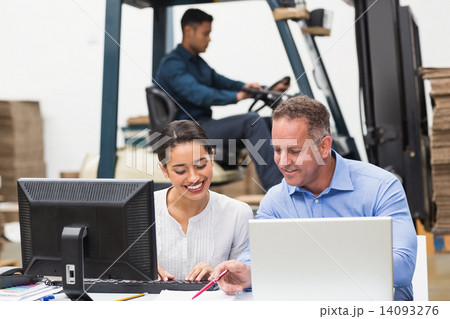 Warehouse managers working with laptop at desk Warehouse managers working with laptop at desk 14093276