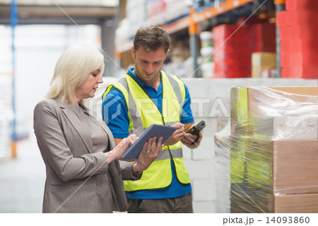 Manager using tablet while worker scanning package 14093860