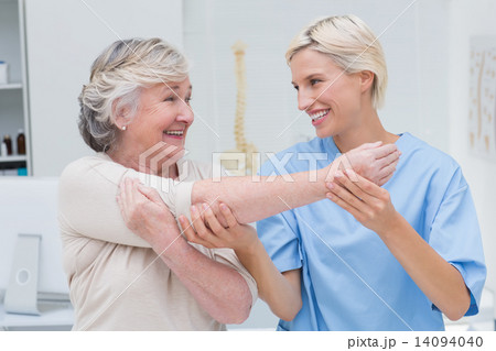 Happy nurse assisting patient in raising arm 14094040