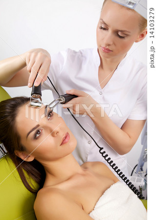 woman having a stimulating facial treatment from a therapist 14103279