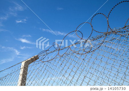 Metal fence with barbed wire over blue sky 14105730