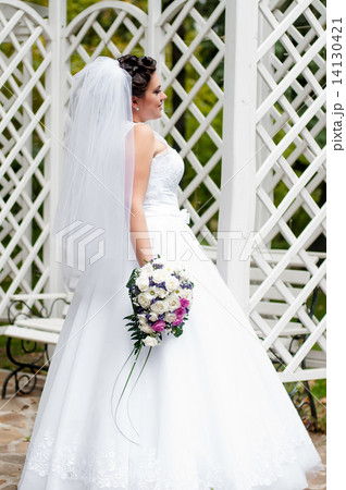 Young bride in a garden in a white dress with a bouquet Young bride in a garden in a white dress with a bouquet 14130421