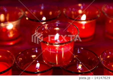 Red tea lights in glass jar illuminates a dark surrounding 14147629