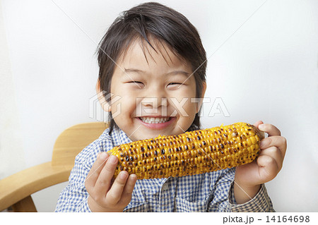 とうもろこしを食べる子供の写真素材