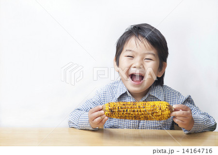 とうもろこしを食べる子供の写真素材