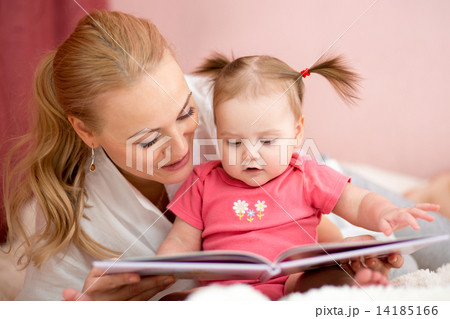 happy mother reads a book to baby girl 14185166