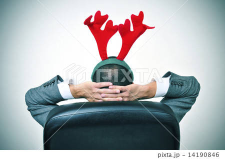 man with a reindeer antlers headband in his office chair man with a reindeer antlers headband in his office chair 14190846