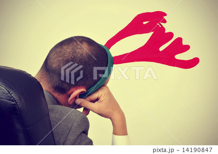 man with a reindeer antlers headband in his office chair, with a 14190847