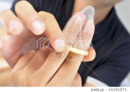 young man unrolling a condom in his fingers young man unrolling a condom in his fingers 14191071