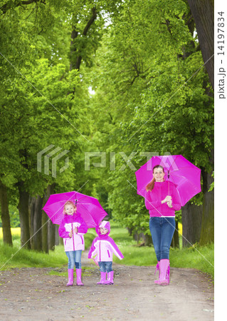 mother and her daughters with umbrellas in spring alley mother and her daughters with umbrellas in spring alley 14197834
