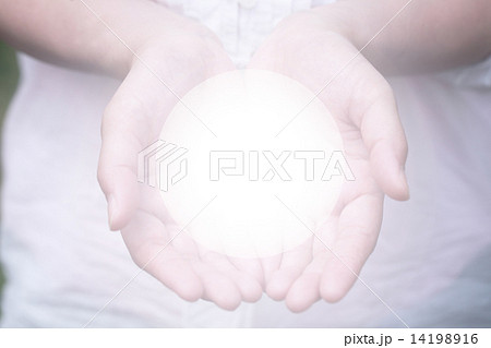 手のひらに光輝く球体の写真素材