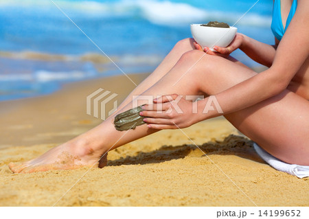 Young slim woman smearing mud mask on the body on the beach Young slim woman smearing mud mask on the body on the beach 14199652