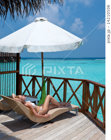 Young woman tans on a water villa terrace , Maldives Young woman tans on a water villa terrace , Maldives 14210506