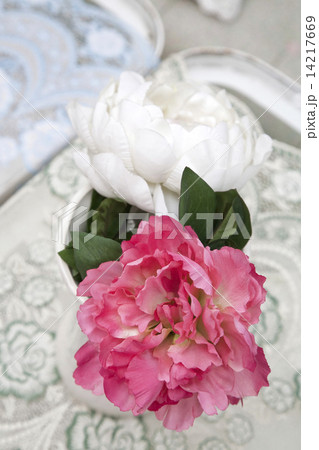 Fake pink and white peonies in white vase on table 14217669