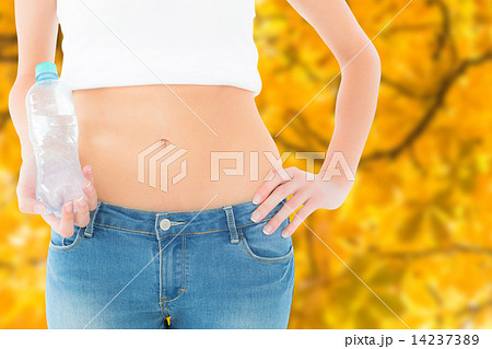 Composite image of mid section of a fit woman holding a bottle o Composite image of mid section of a fit woman holding a bottle o 14237389