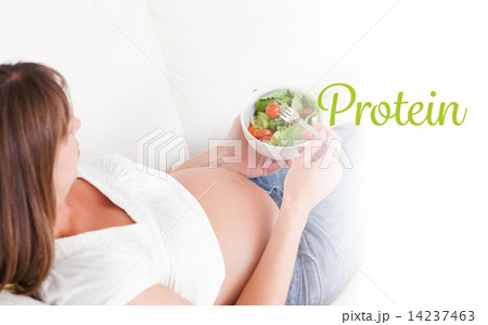 Protein against charming pregnant woman eating a salad while lyi Protein against charming pregnant woman eating a salad while lyi 14237463