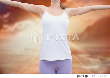 Composite image of woman standing with arms raised on countrysid 14237558