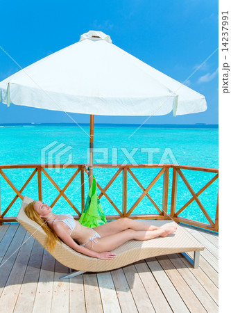 Young woman tans on a water villa terrace , Maldives Young woman tans on a water villa terrace , Maldives 14237991