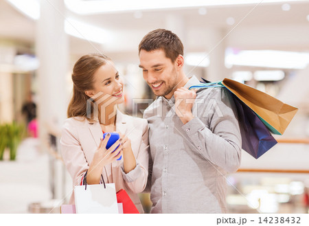 couple with smartphone and shopping bags in mall 14238432