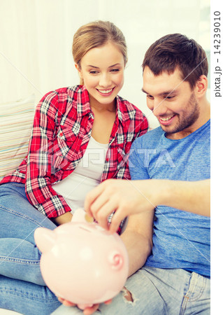smiling couple with piggybank sitting on sofa 14239010
