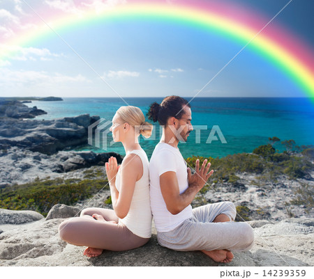 happy couple meditating in lotus pose on beach 14239359