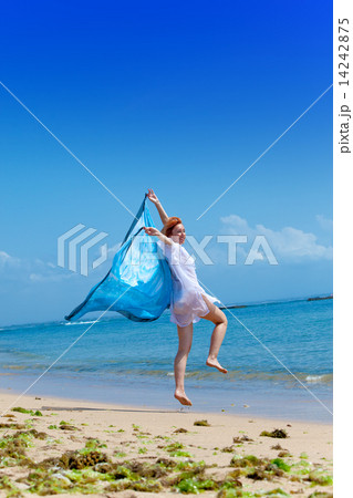 The young attractive woman jumping with a blue scarf in hands.. The young attractive woman jumping with a blue scarf in hands.. 14242875