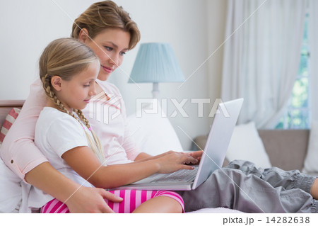Mother and daughter using laptop in bed 14282638