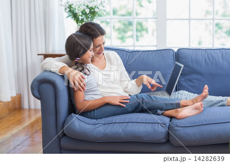 Happy mother and daughter sitting on the couch and using laptop Happy mother and daughter sitting on the couch and using laptop 14282639