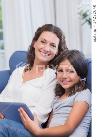 Happy mother and daughter sitting on the couch and using tablet Happy mother and daughter sitting on the couch and using tablet 14282640