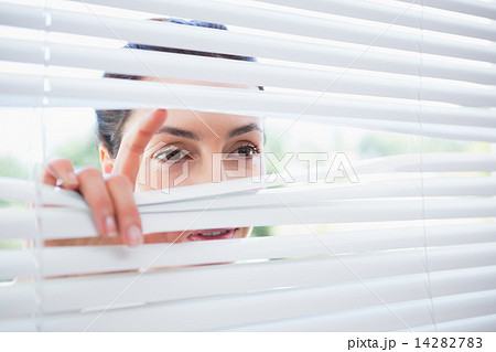 Woman peeking through blinds Woman peeking through blinds 14282783