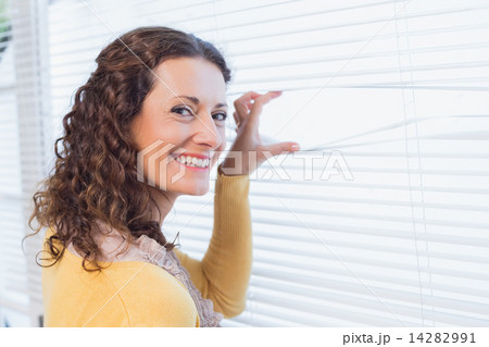 Curious woman looking through blinds 14282991