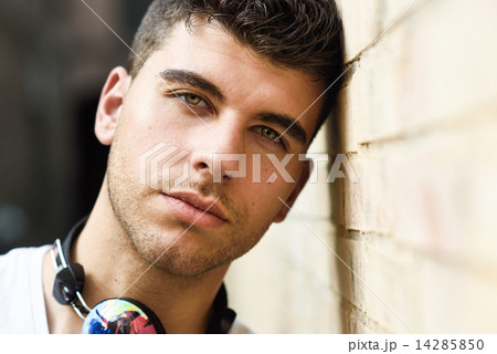Young man in urban background listening to music with headphones Young man in urban background listening to music with headphones 14285850