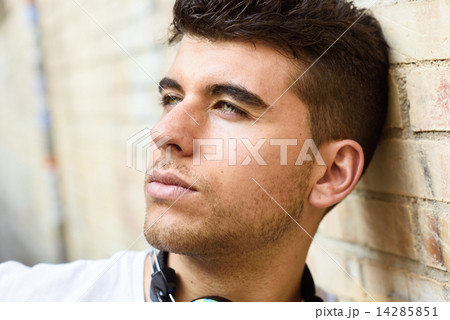 Handsome young man with blue eyes posing near a wall 14285851